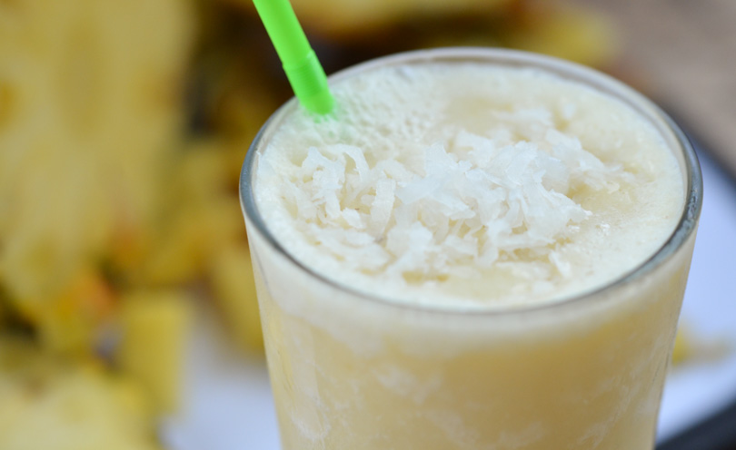 Pina colada smoothie with green straw.