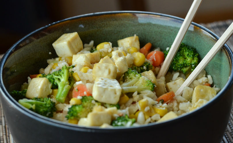 Cauliflower fried rice in bowl with chopsticks.