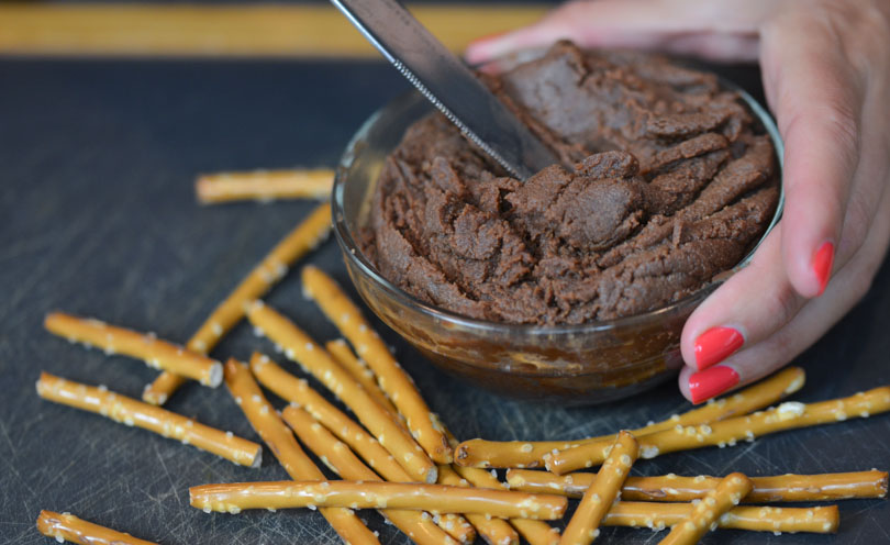 Chocolate almond butter served from small glass dish with knife.